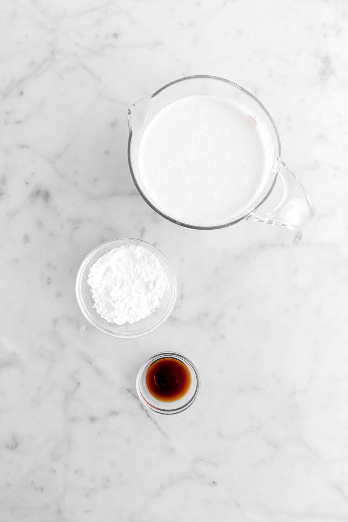 heavy cream, powdered sugar, and vanilla on marble surface.