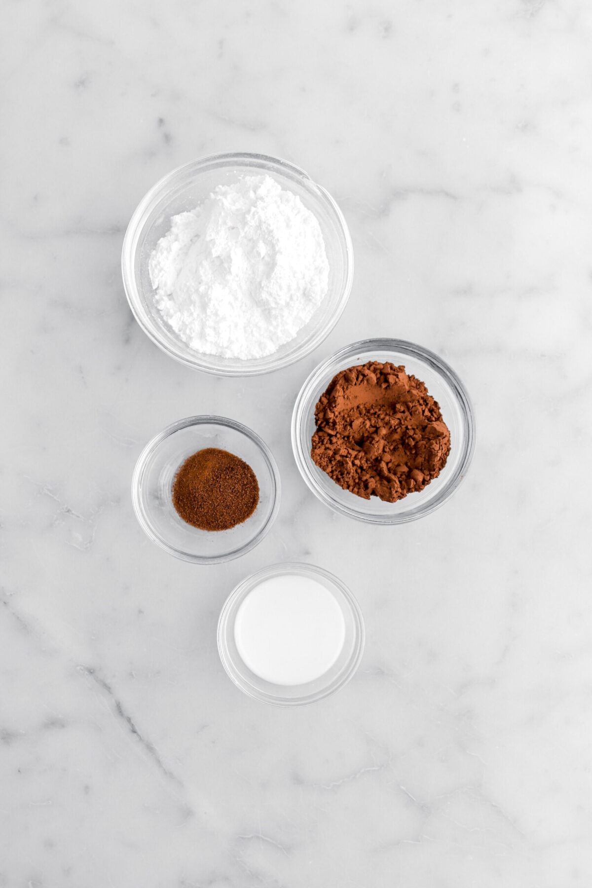 powdered sugar, cocoa powder, espresso powder, and milk on marble surface.