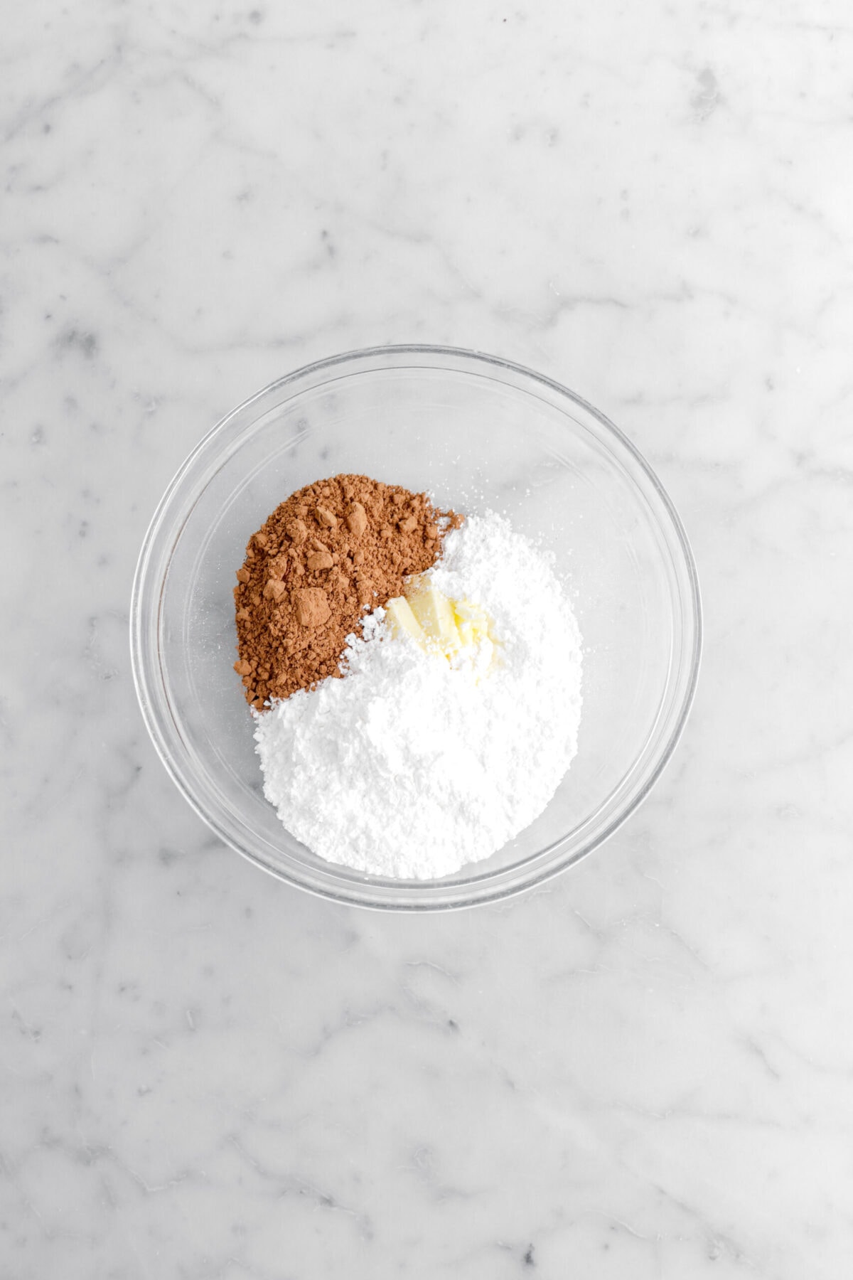 cocoa powder, butter, and powdered sugar in glass bowl.