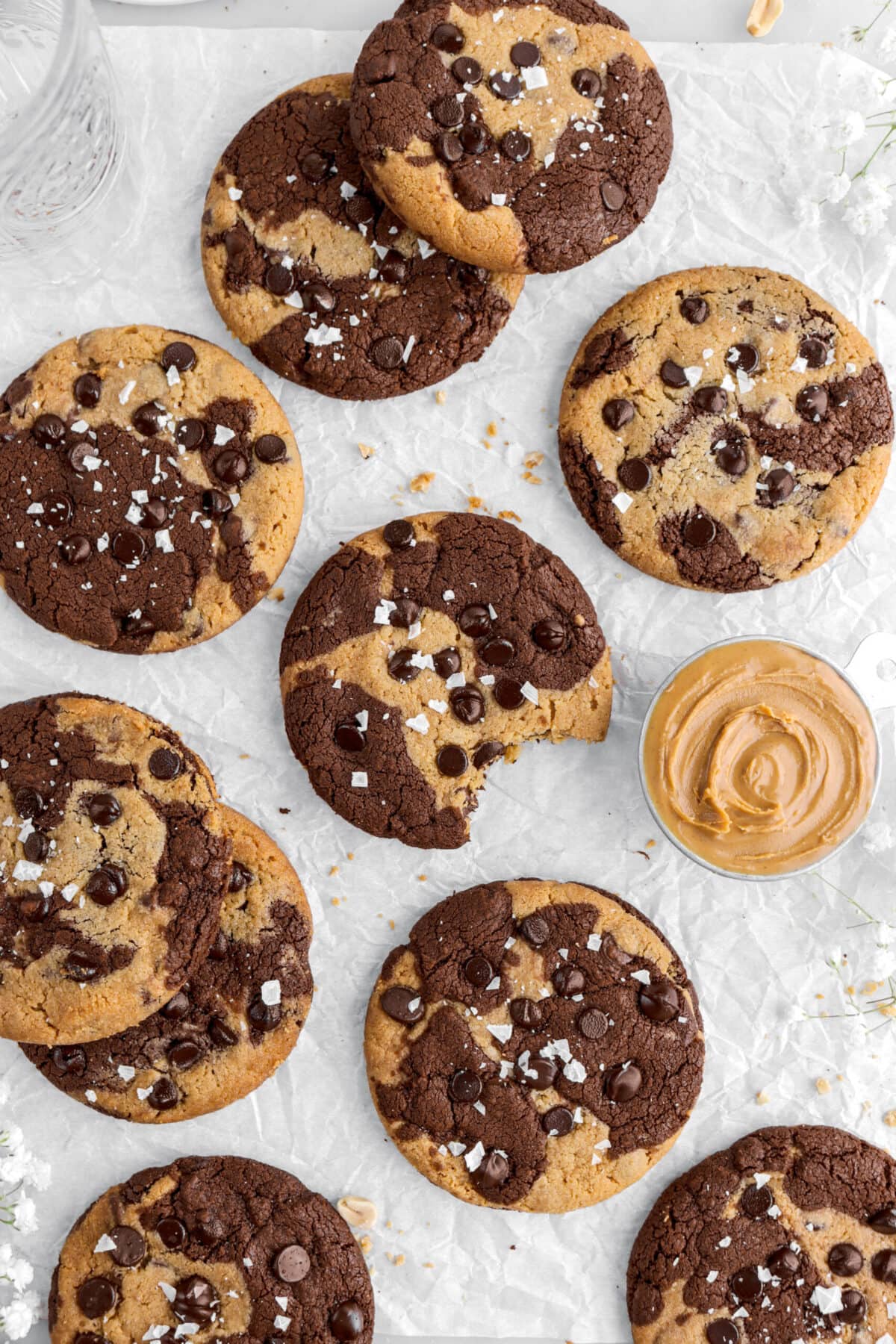 chocolate peanut butter marble cookies with one cookie missing a bite on parchment paper.