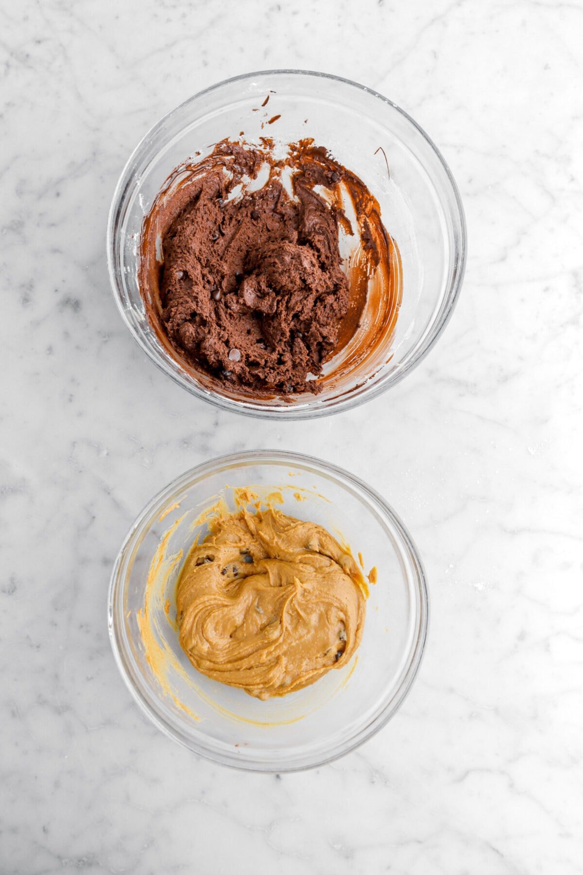 chocolate cookie dough and peanut butter cookie dough in two separate glass bowls.