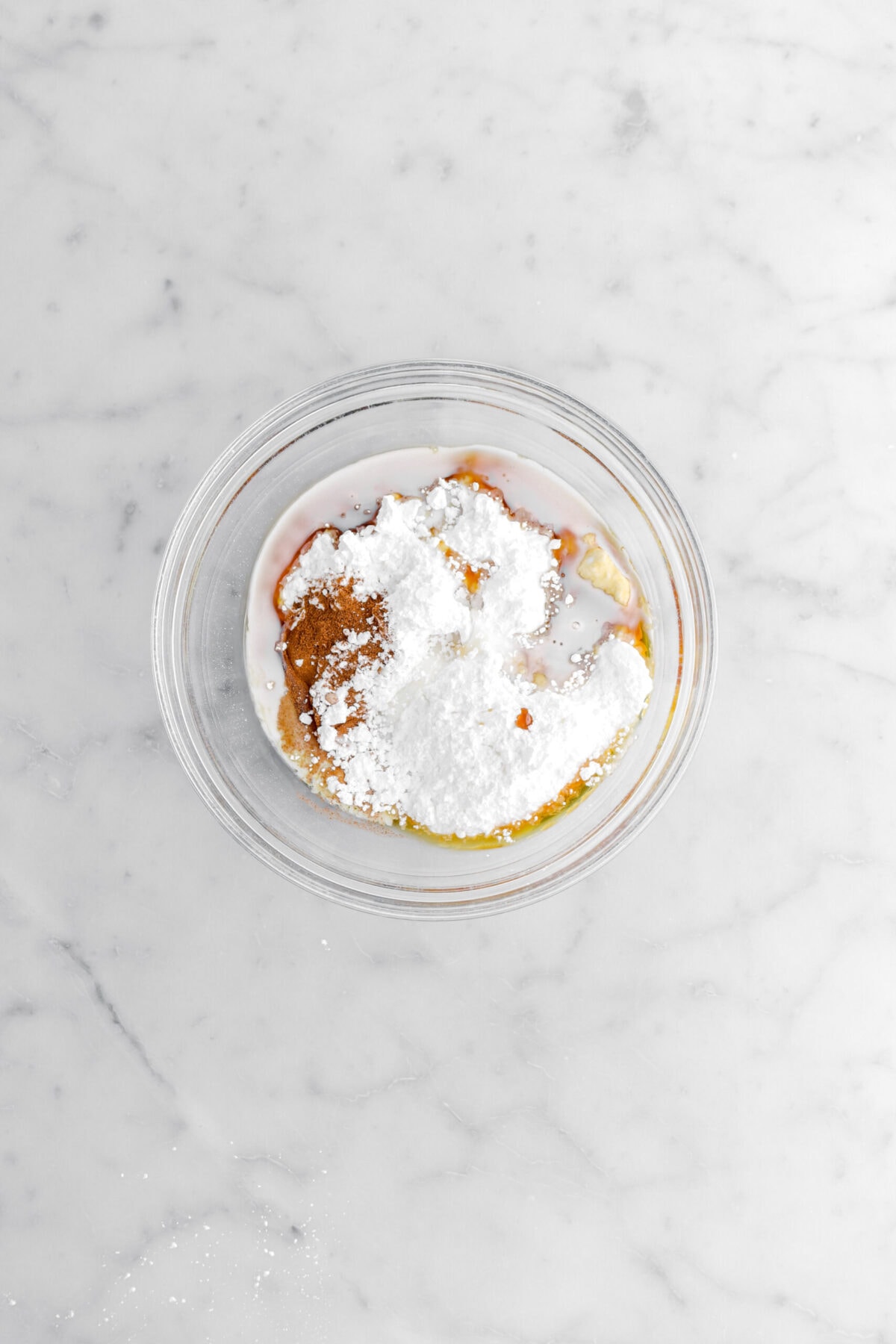 powdered sugar, spice, maple syrup, and milk in glass bowl.