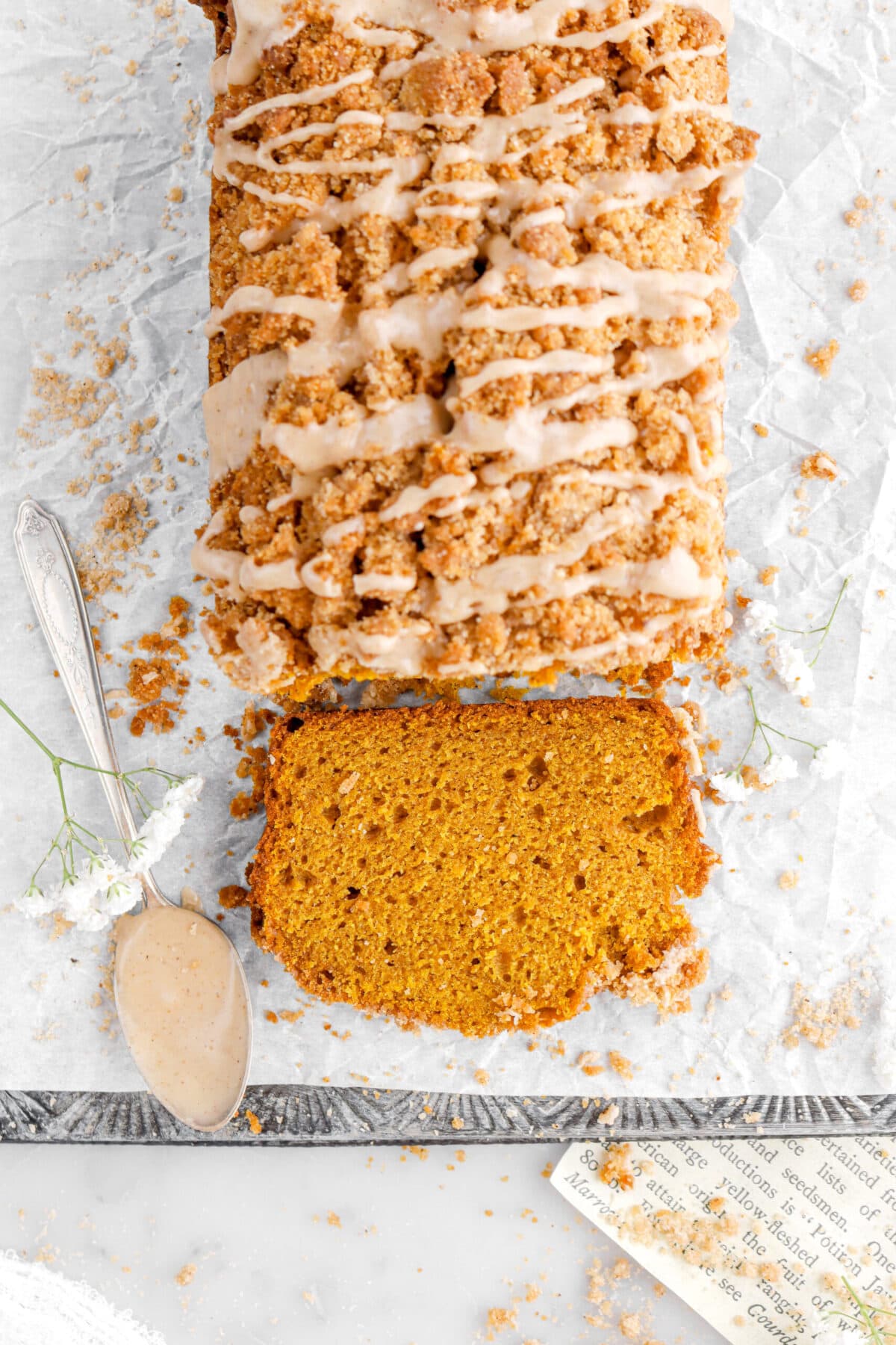 overhead image of slice of pumpkin bread laying in front of cake on upside down sheet pan.
