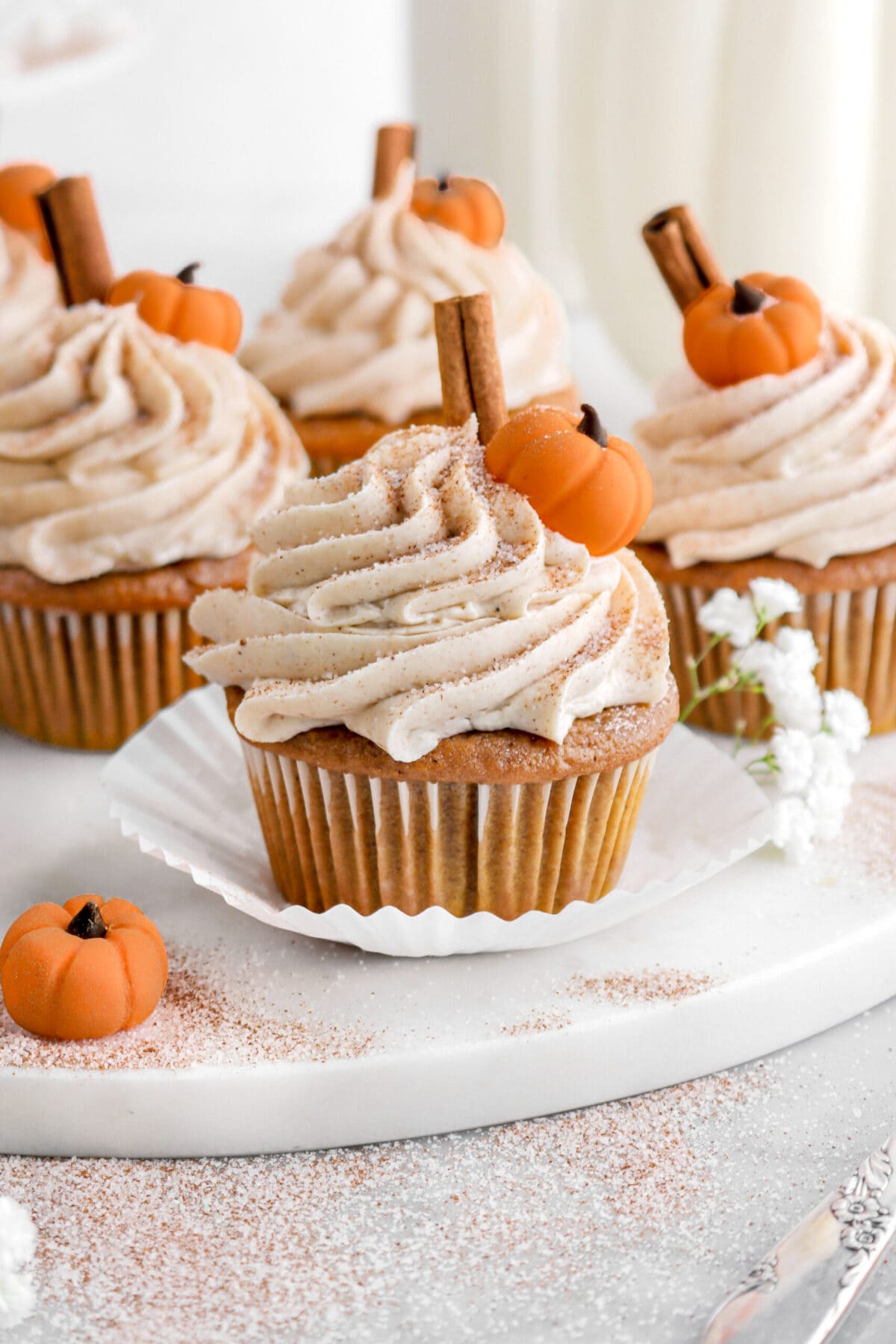 pumpkin cupcake on marble tray with more pumpkin cupcakes behind.