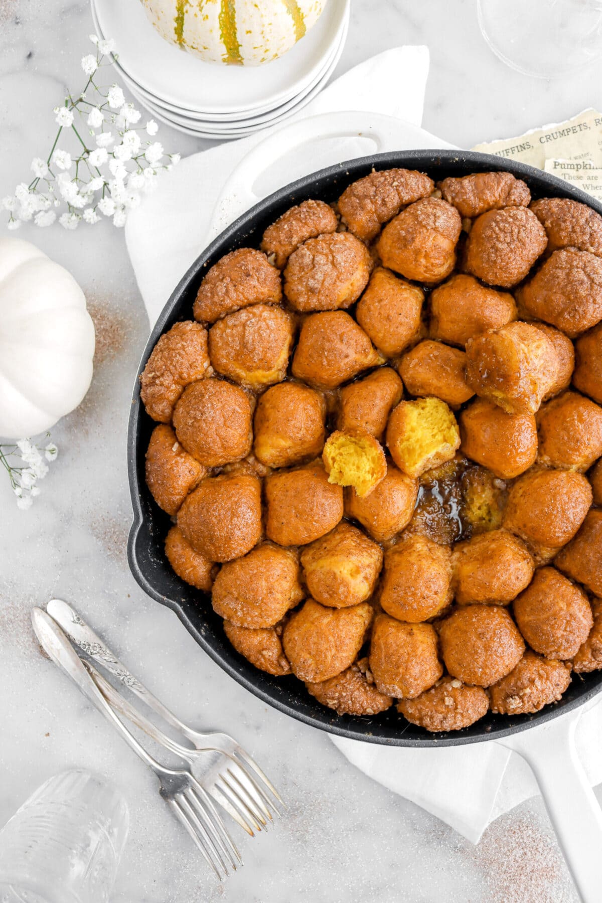 cropped overhead image of pumpkin monkey bread in skillet with pumpkins around.