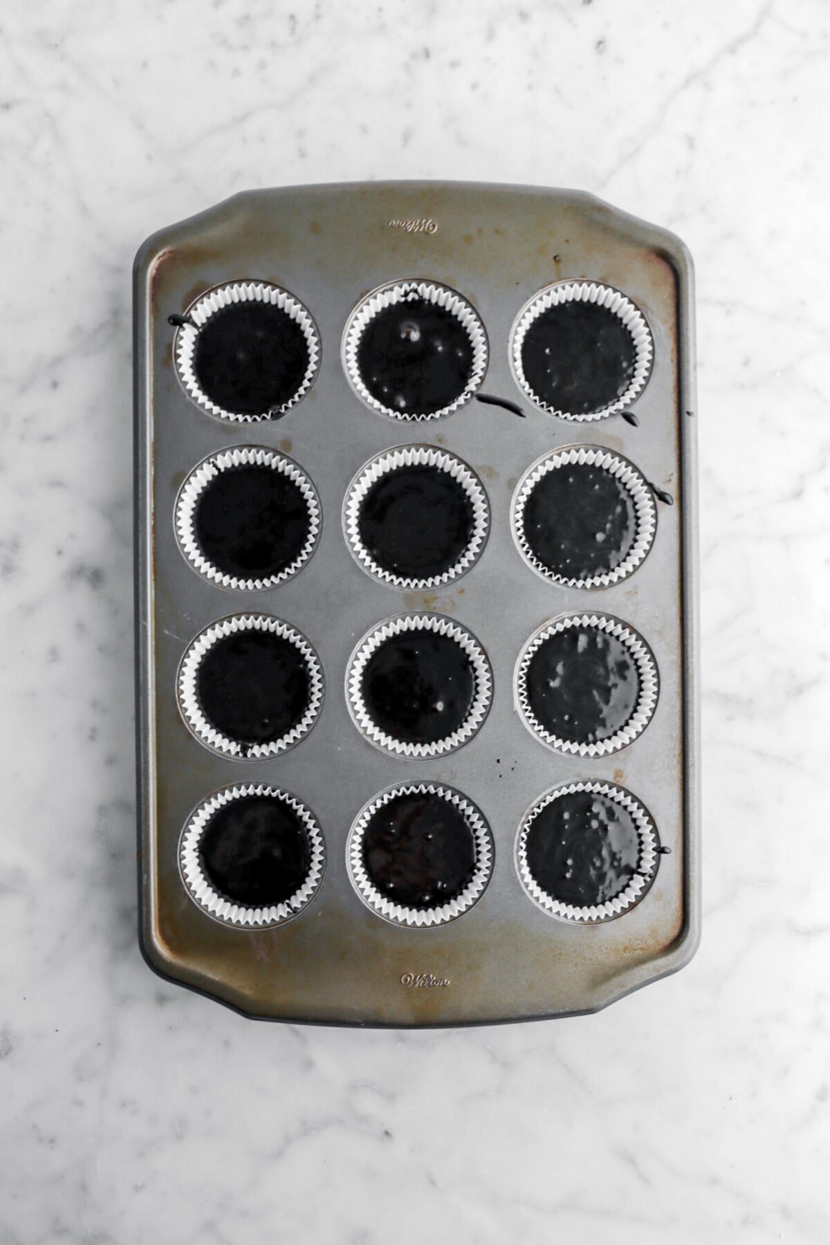 black cake batter in muffin pan.