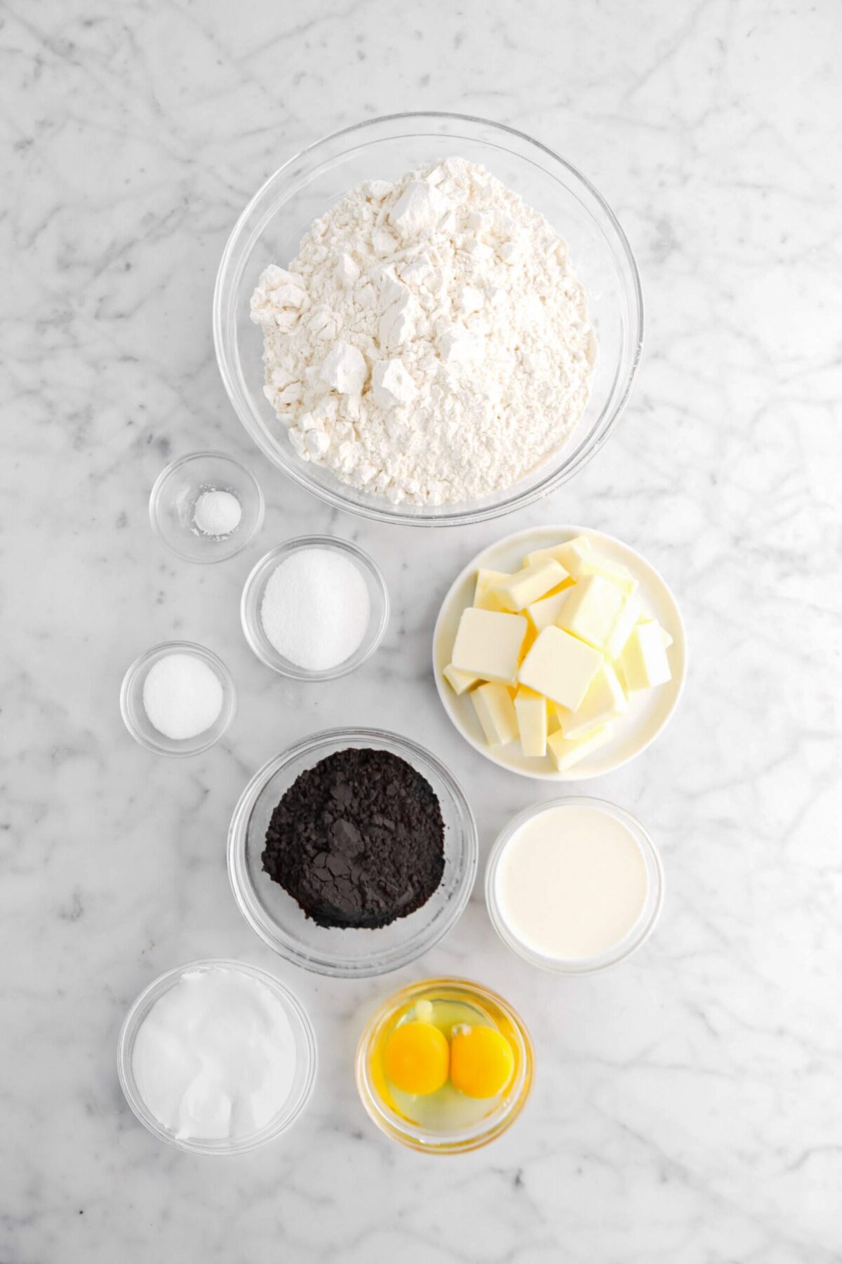 flour, baking soda, sugar salt, butter, black cocoa powder, milk, eggs, and marshmallow fluff on marble surface.