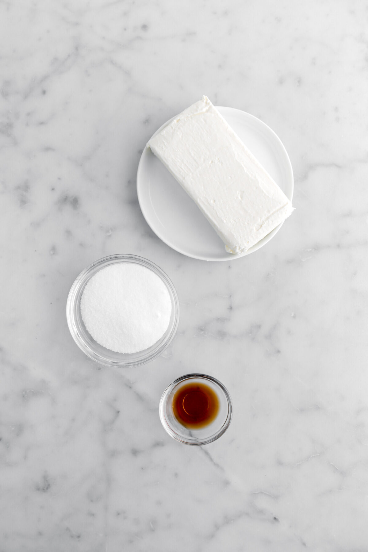 cream cheese, sugar, and vanilla on marble surface.