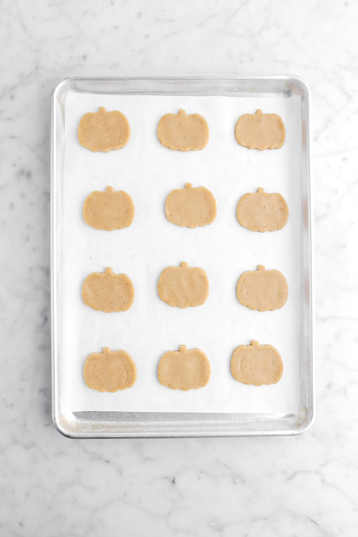 pumpkin shaped cookie dough on lined sheet pan.