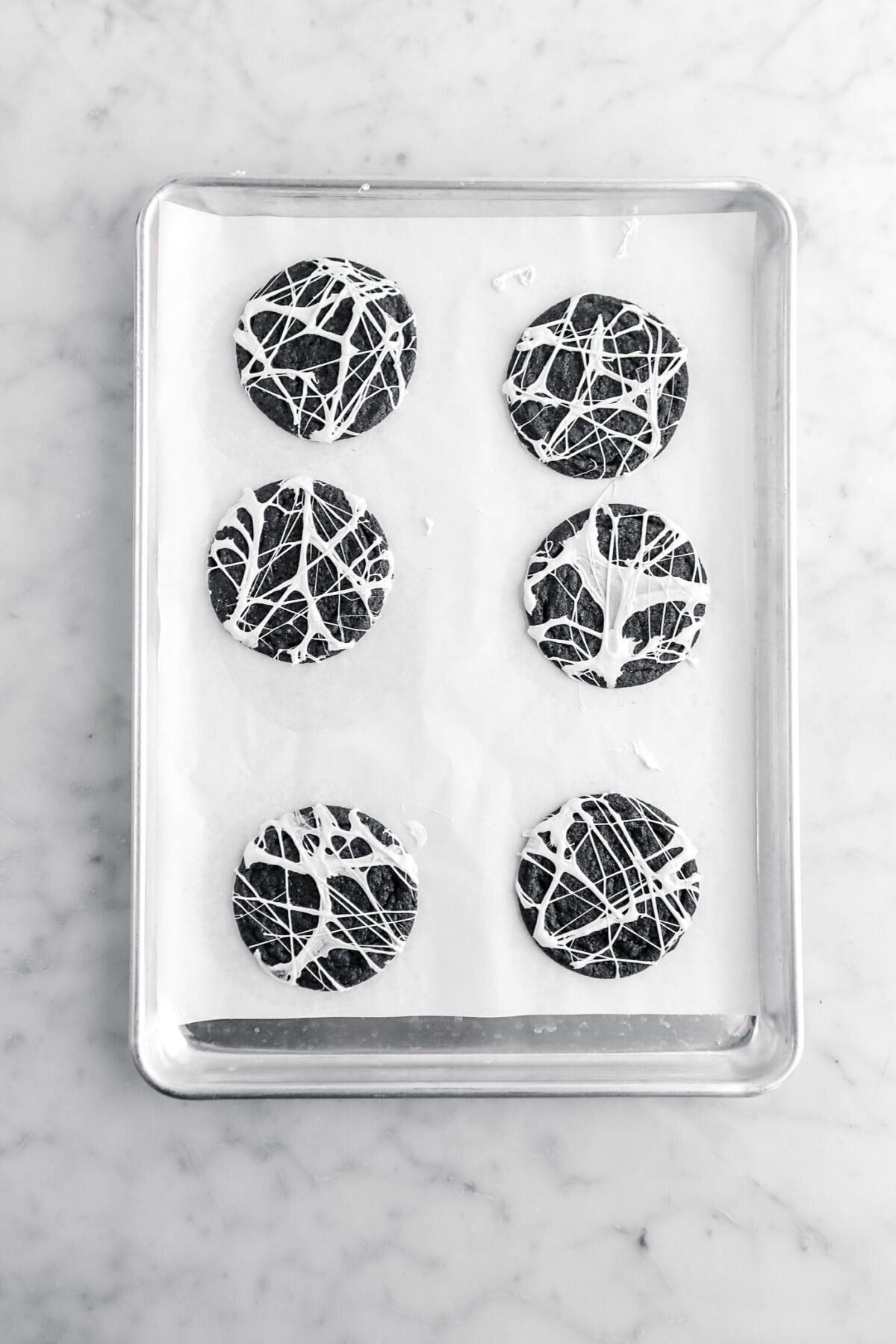 six cookies with melted marshmallow on top on lined sheet pan.