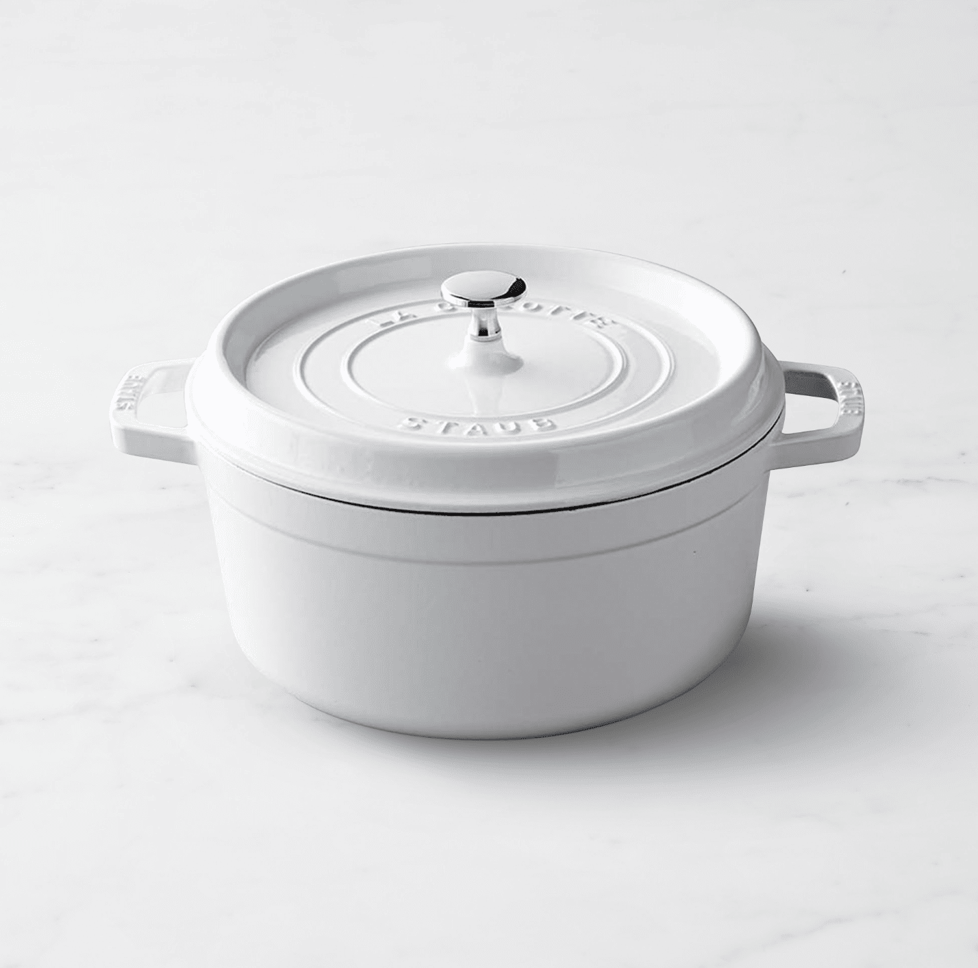 white staub dutch oven on marble surface.