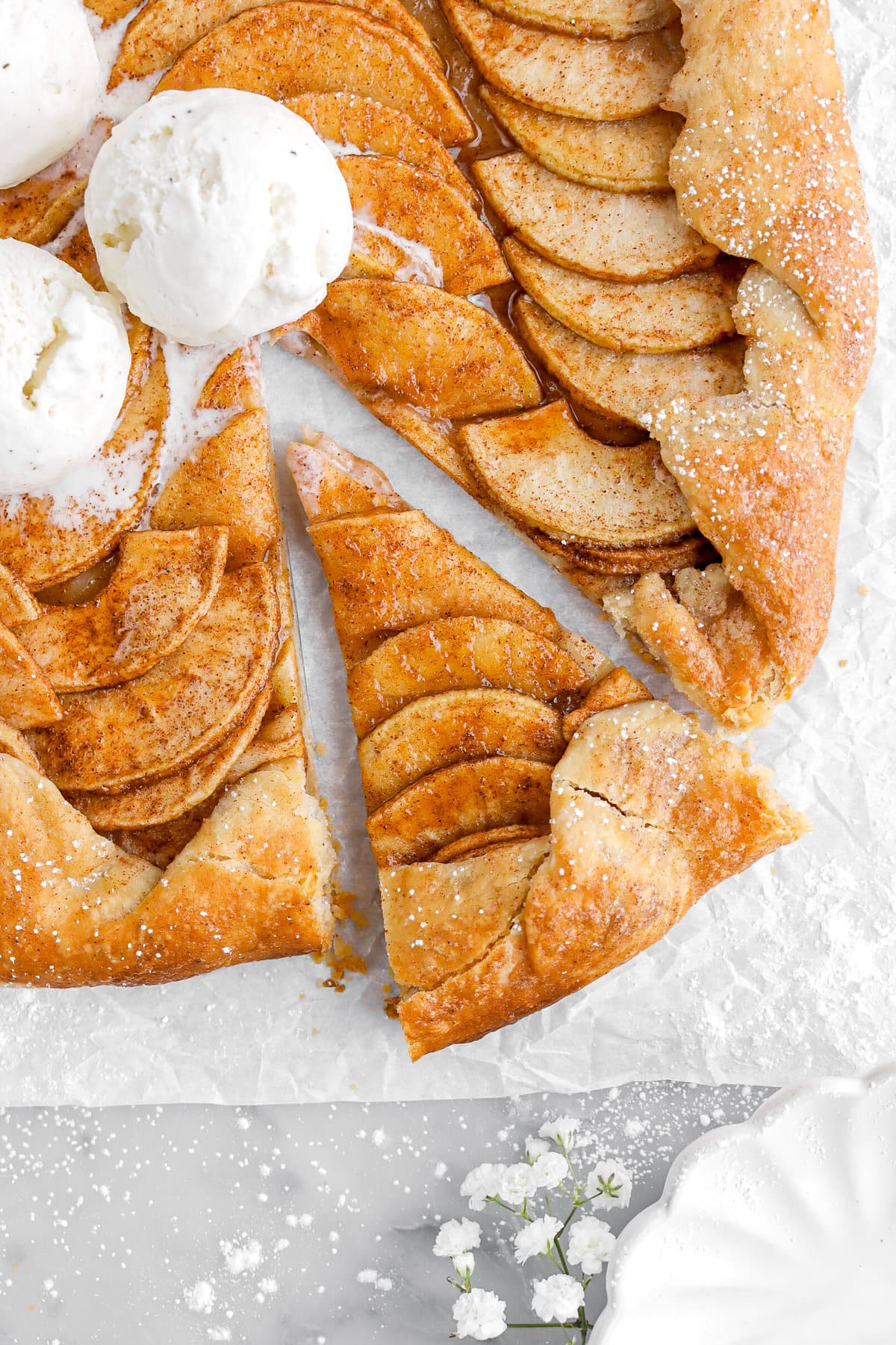 close up overhead image of slightly pulled away slice of apple galette on parchment paper.