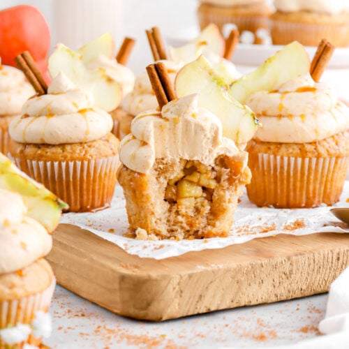 apple pie cupcakes on wood board with front cupcake missing a bite.