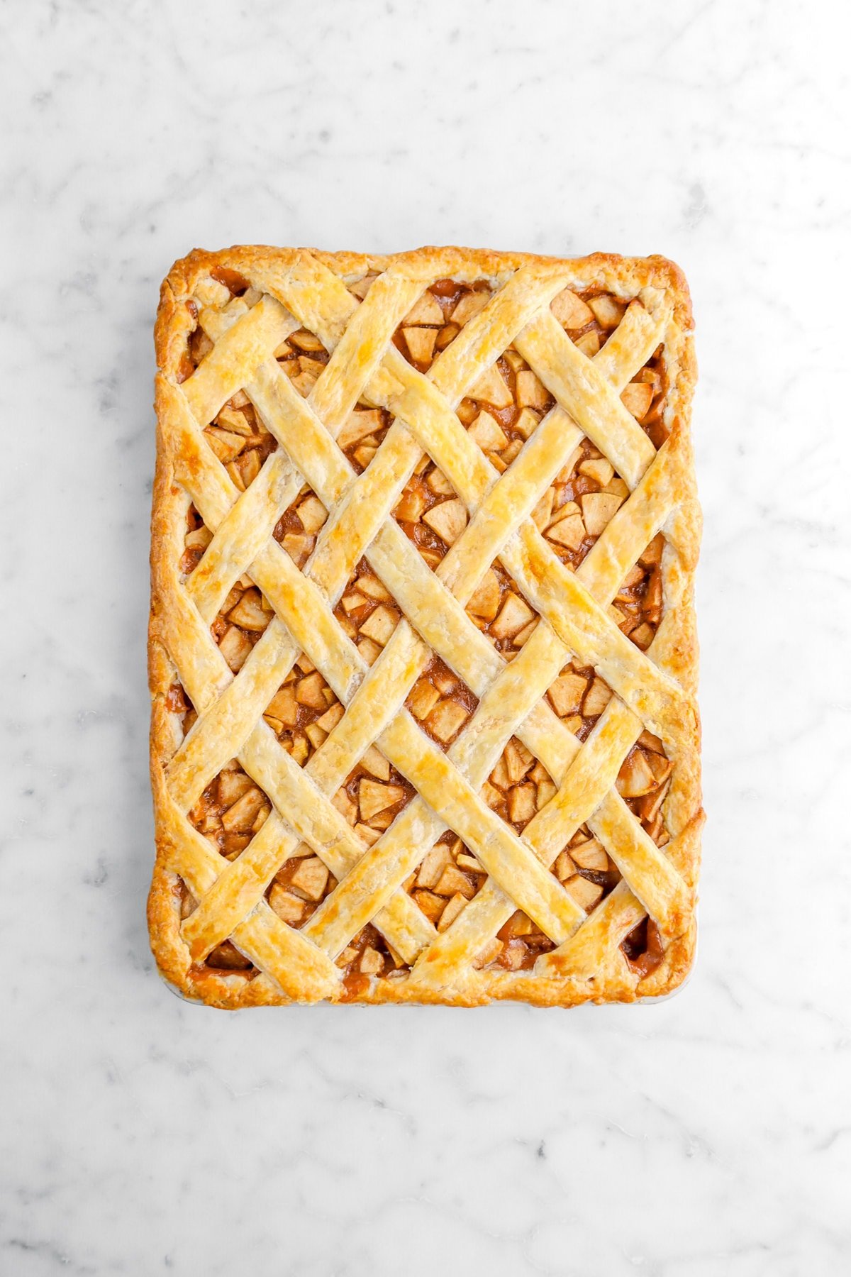 baked apple slab pie on marble surface with lattice top.
