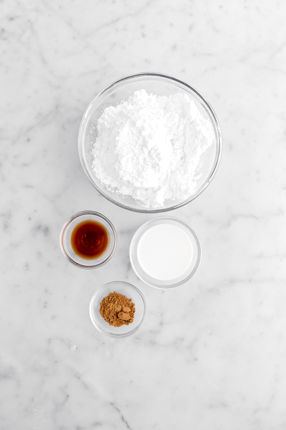 powdered sugar, vanilla, milk, and sipce on marble surface.