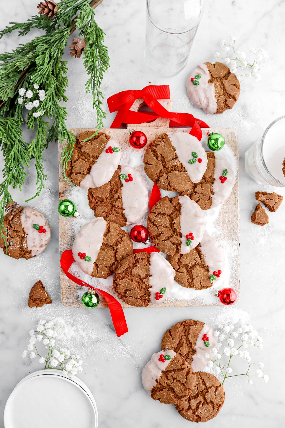 gingerbread crinkle cookies on square wood board with red ribbon, greenery, and flowers around.