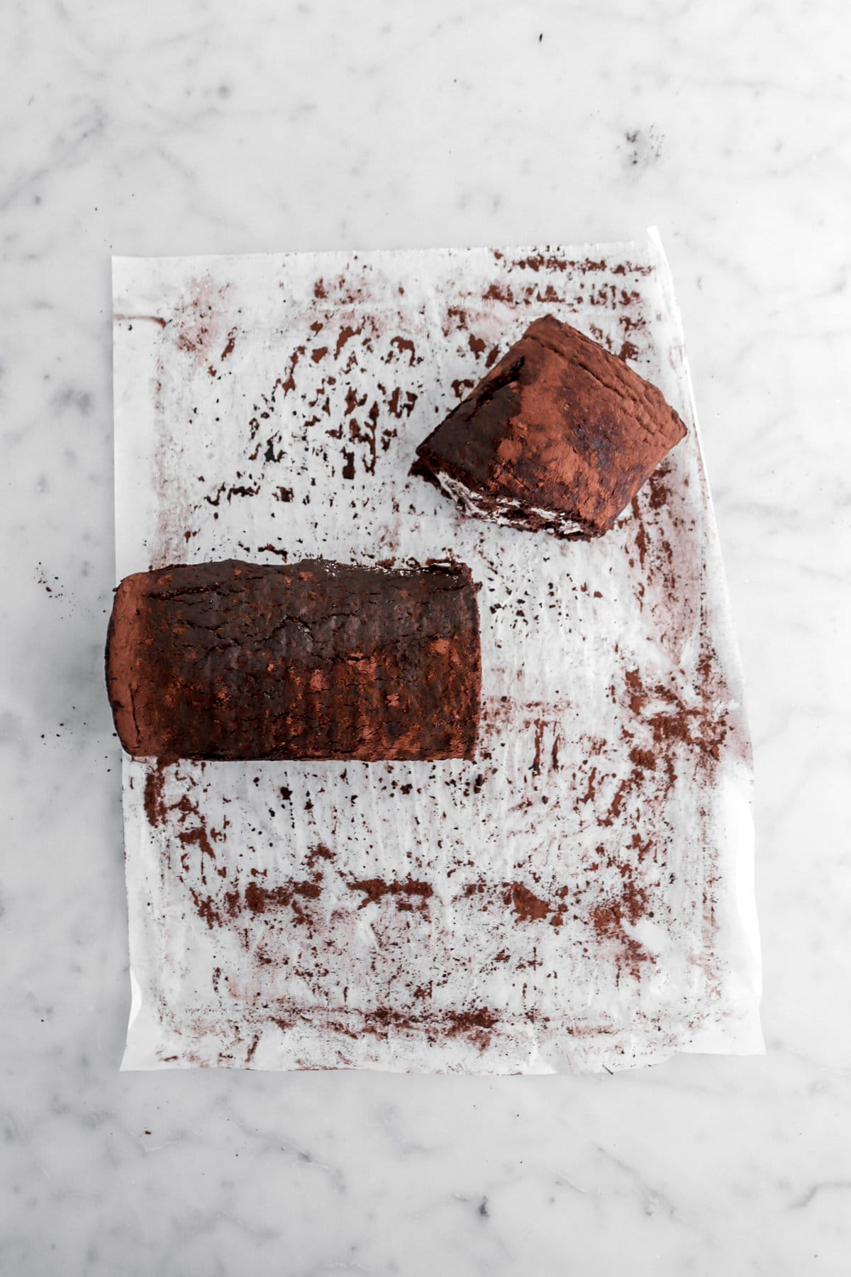 chocolate cake roll cut into two pieces on parchment paper.