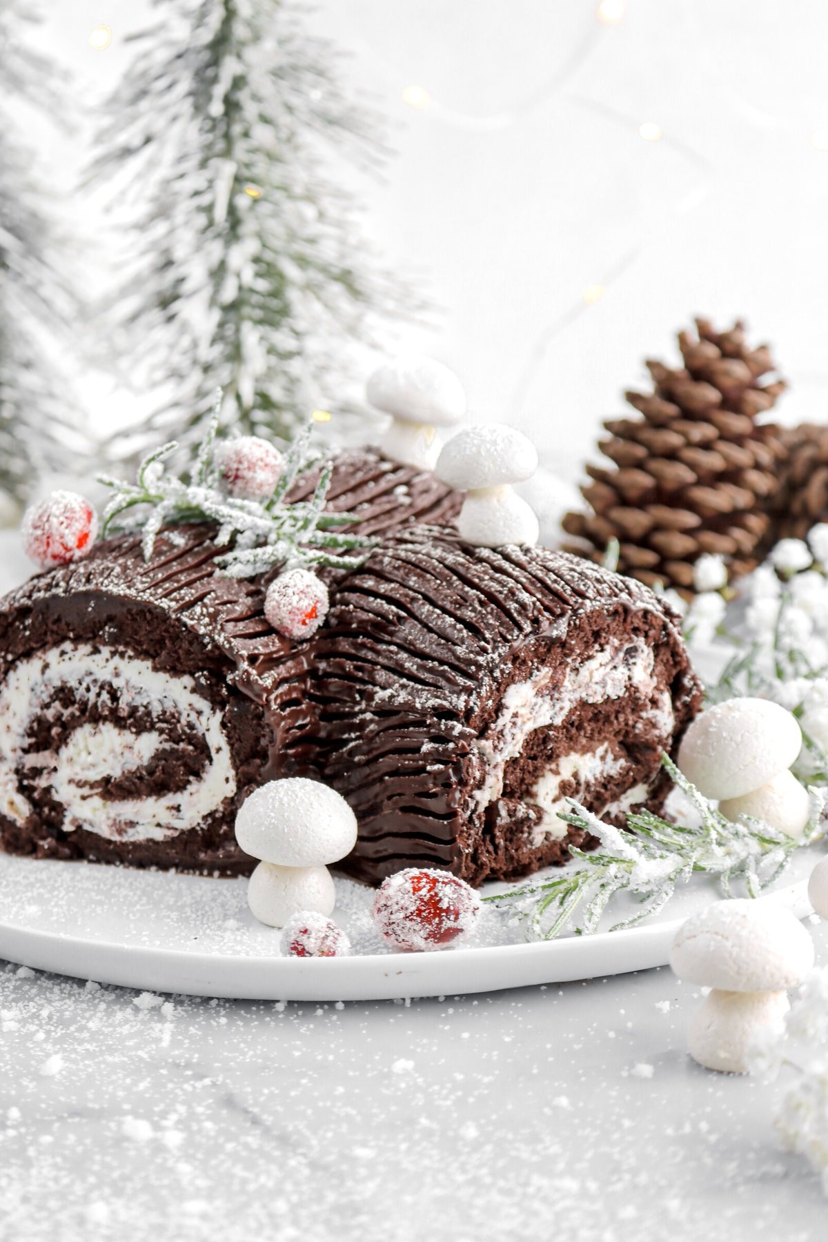 cropped lose up of right side of chocolate yule log with meringue mushrooms around.