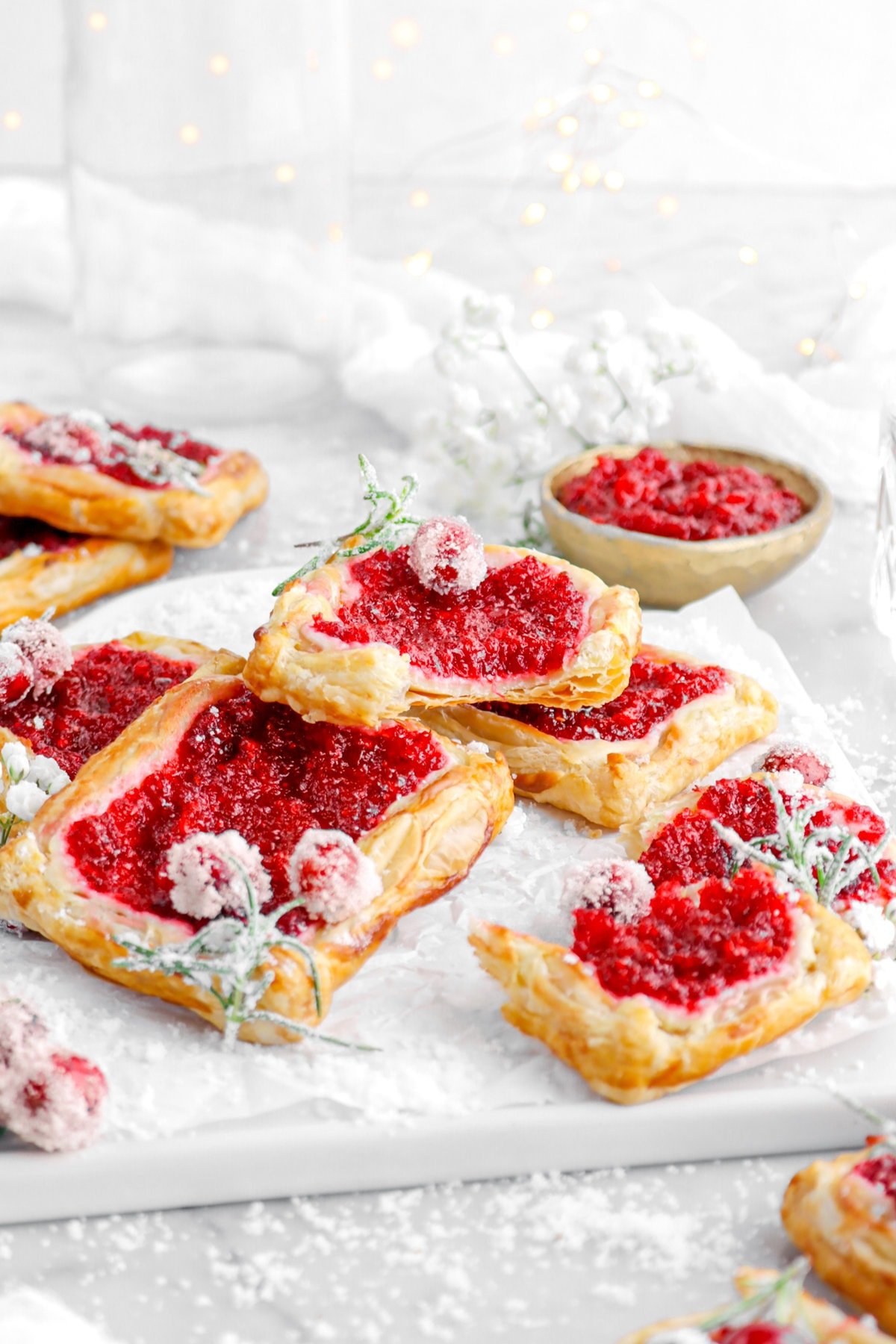 pulled back angled image of cranberry puff pastry tarts on square serving plate.
