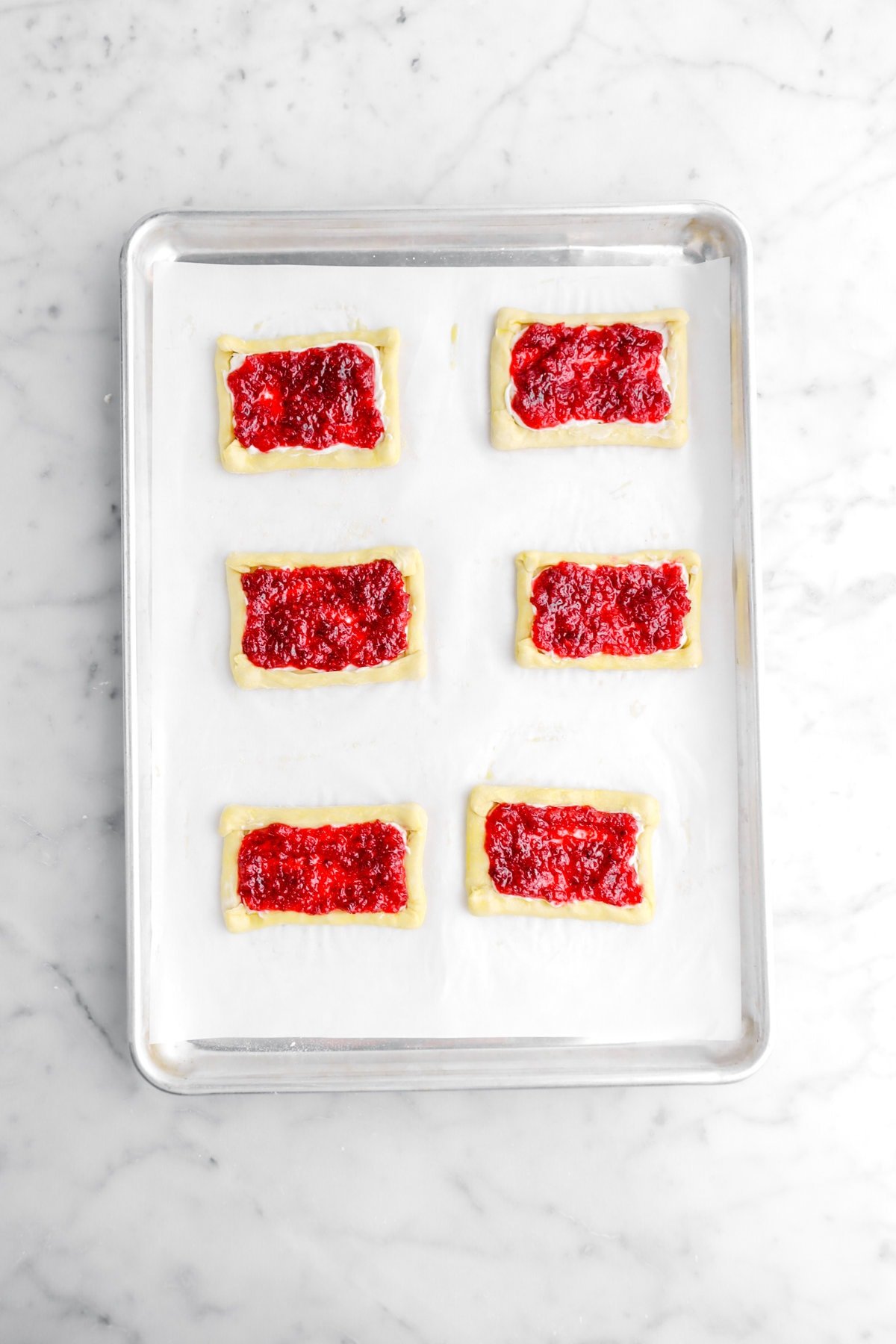 unbaked mini cranberry tarts on lined sheet pan.