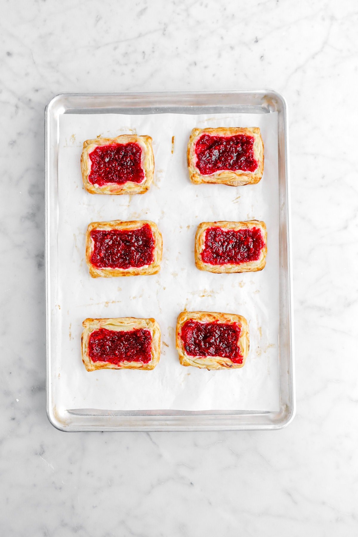 six baked puff pastry tarts on lined sheet pan.