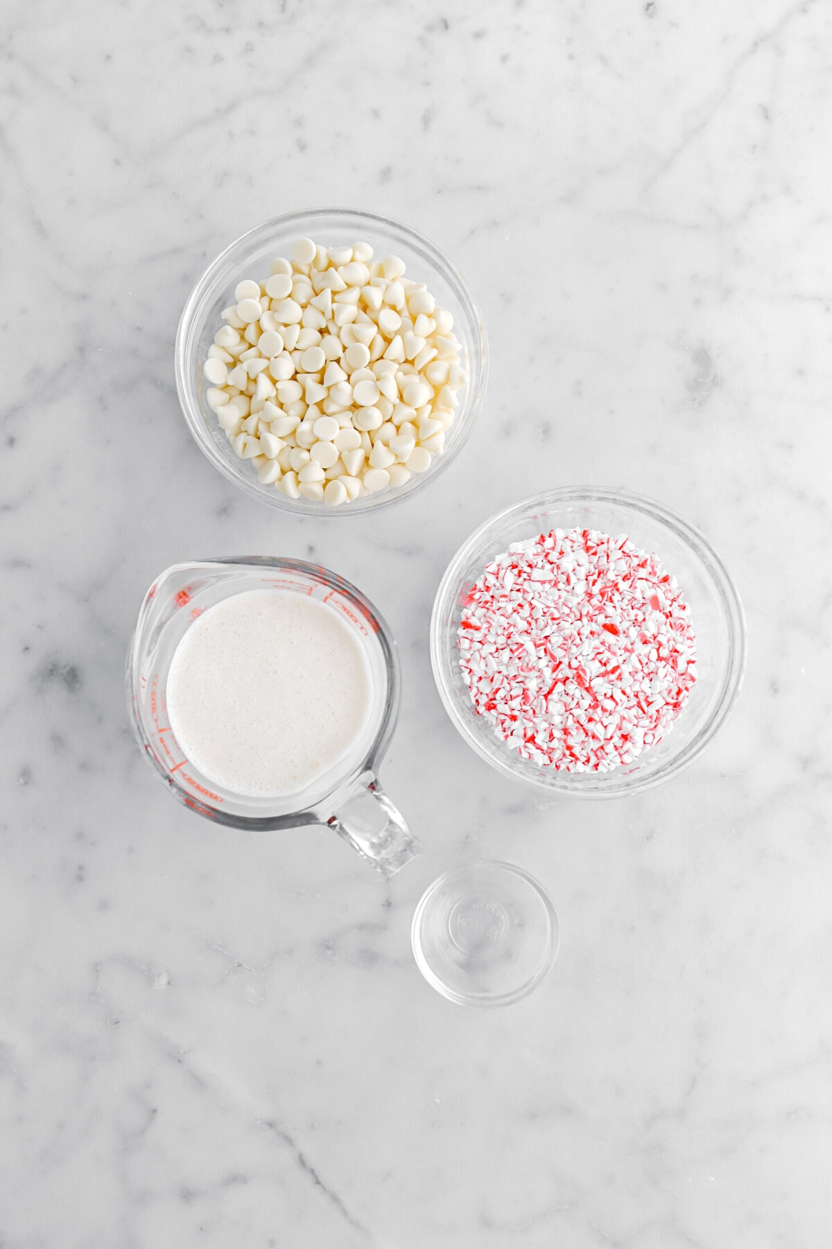 white chocolate chips, cream, crushed candy canes, and peppermint extract on marble surface.