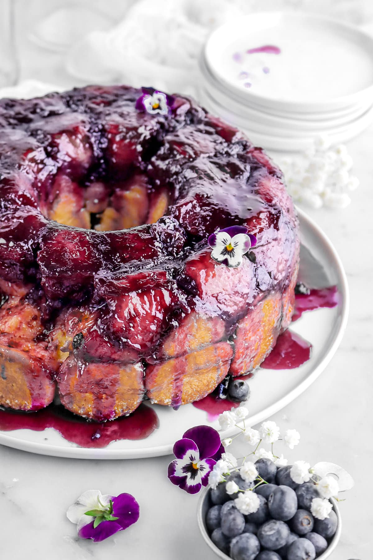 cropped image of lemon blueberry monkey bread with violas and blueberries around.