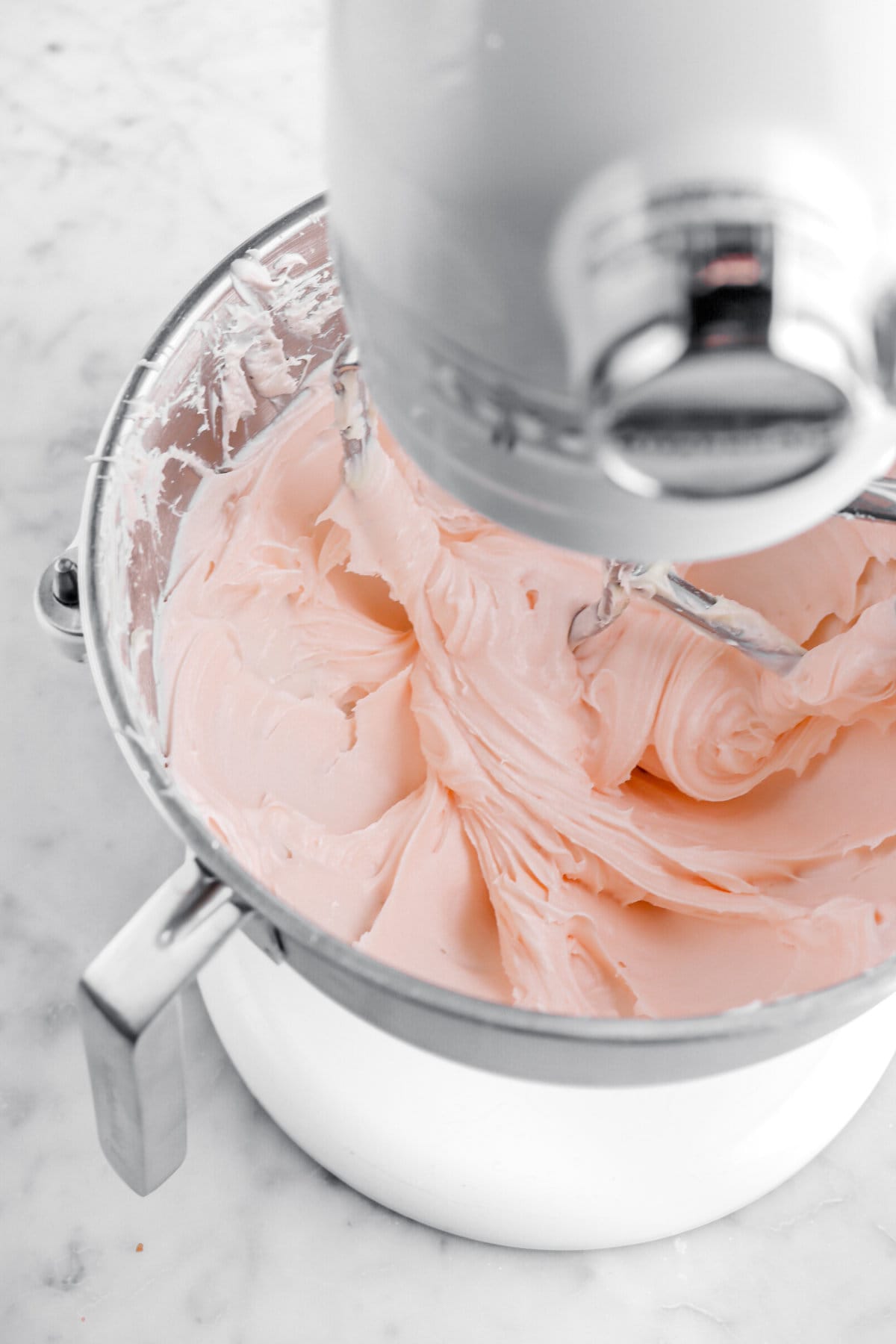 pastel pink cream cheese frosting in stand mixer.