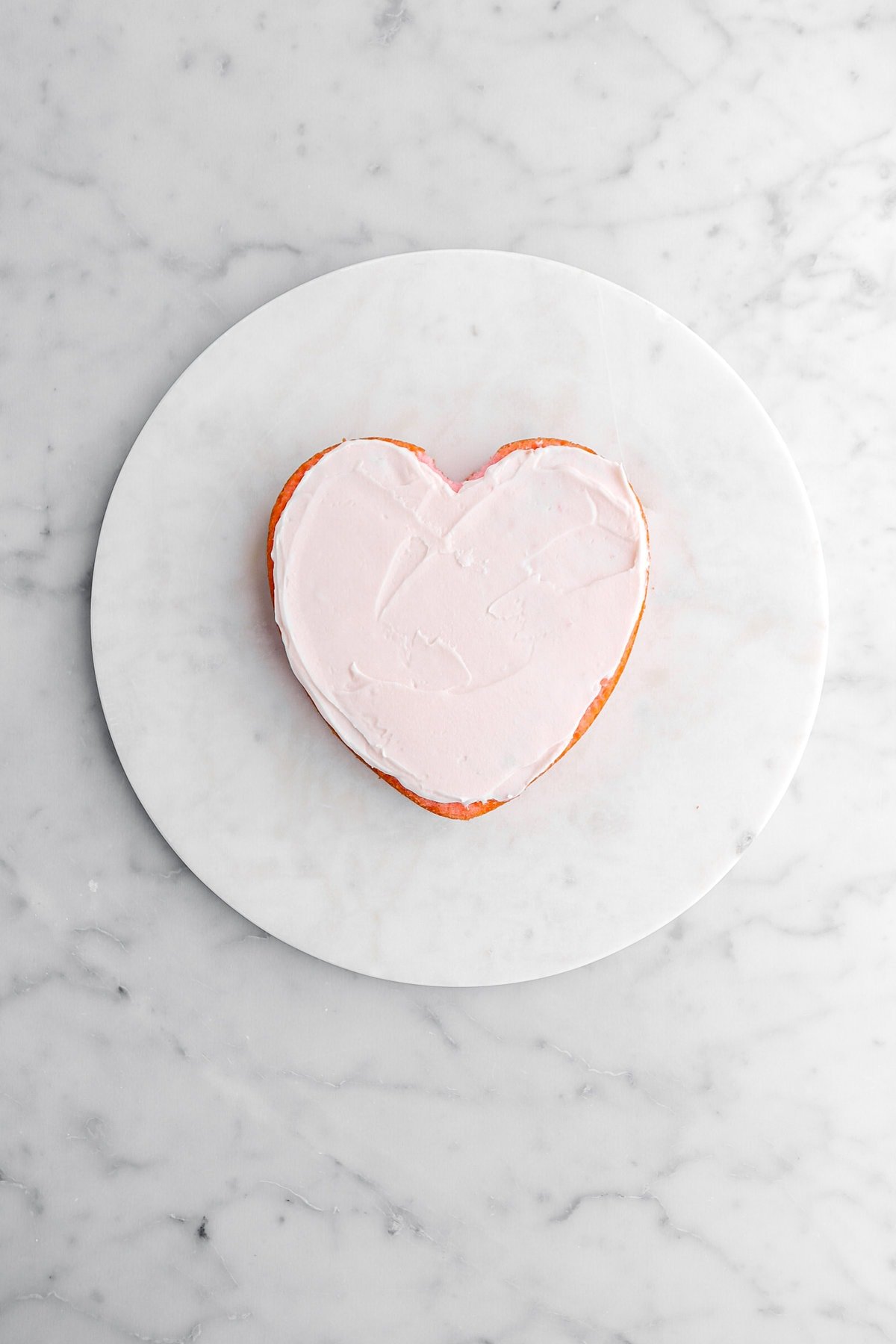 pink frosting spread across heart shaped cake.