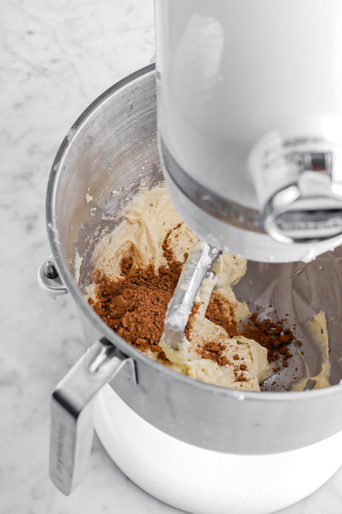half of cake batter in stand mixer with cocoa powder on top.