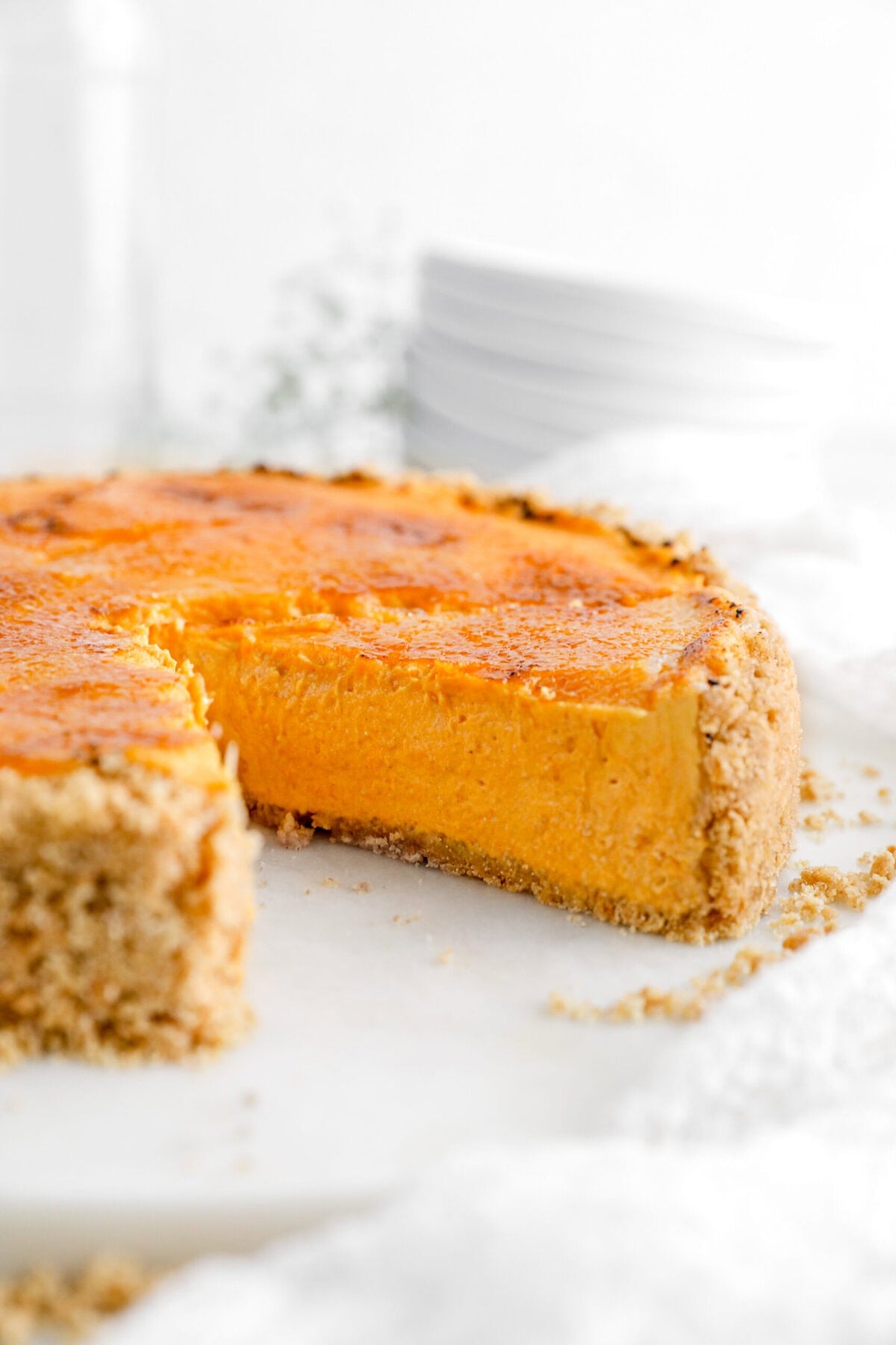 Close-up of a pumpkin cheesecake with a slice removed, showing creamy filling and crust.