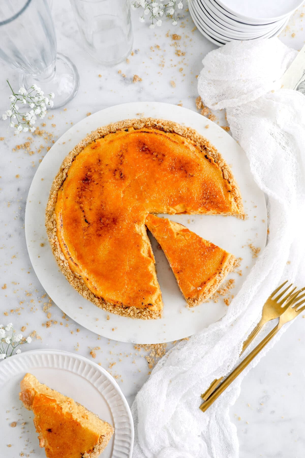 Bruleed pumpkin cheesecake on marble surface with slice taken out.