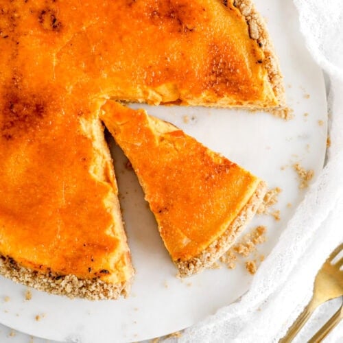 Delicious pumpkin cheesecake with a graham cracker crust on a white plate.