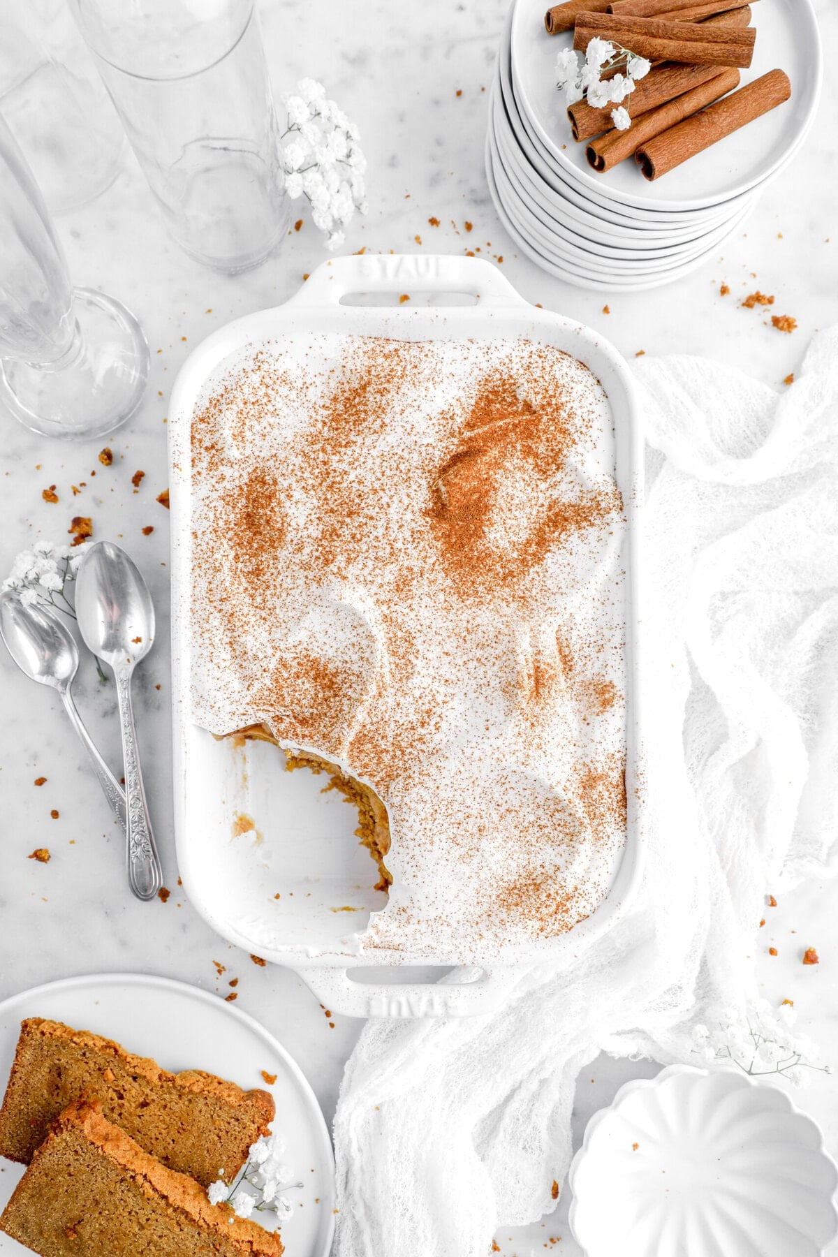 pumpkin bread pudding in white casserole with slices of pumpkin bread beside.