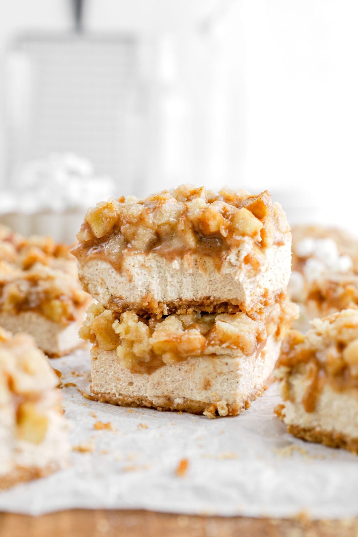 two stacked apple pie cheesecake bars with top slice missing a bite.